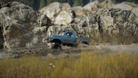 a blue truck driving through a muddy area